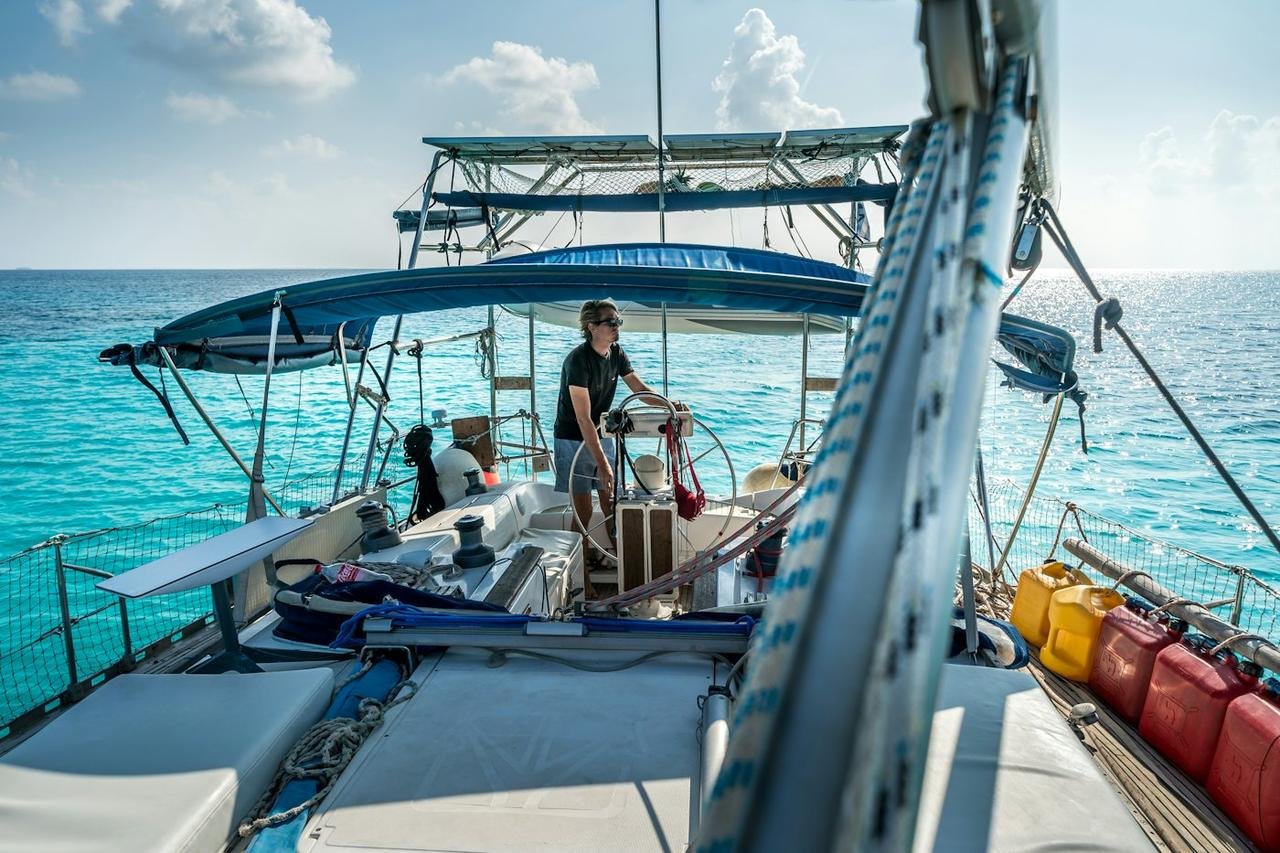 Delivery captain at the wheel of a cruising sailboat on clear blue water
