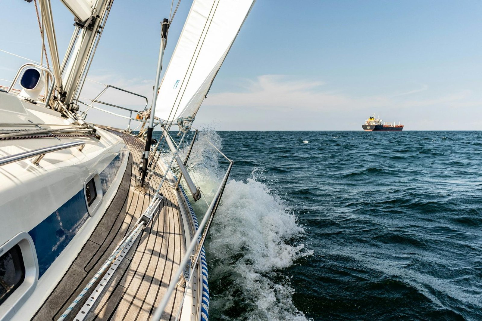 Sailboat heeled under sail on the open Atlantic, bow wave breaking along the hull during an offshore yacht delivery